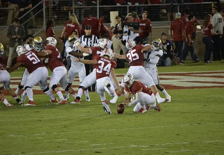 Stanford Cardinal football players in action on the field at Stanford Stadium during a night game