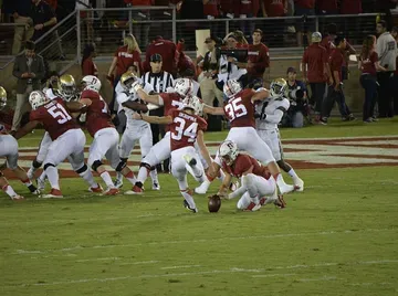 Stanford Cardinal football players in action on the field at Stanford Stadium during a night game